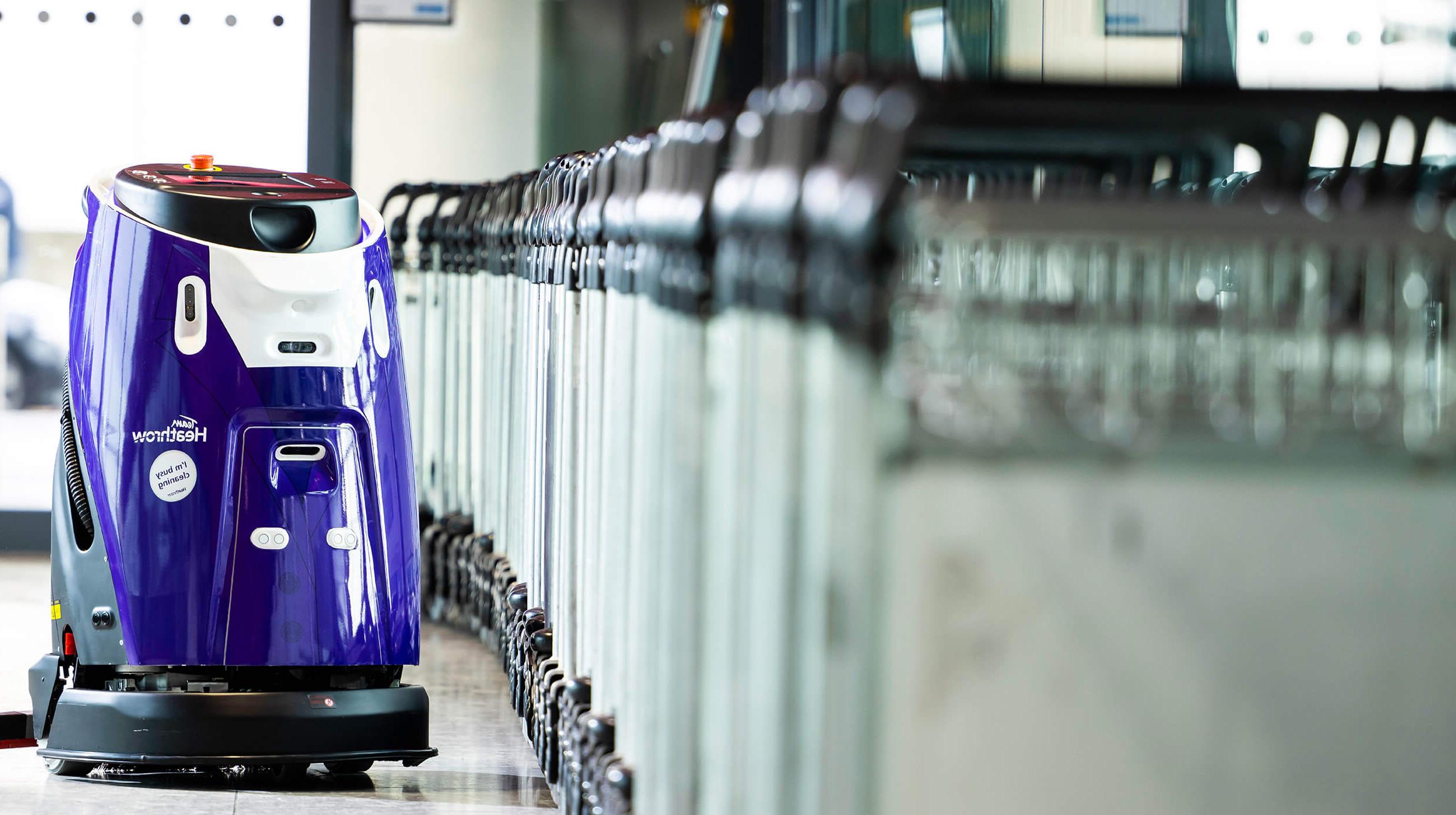 Mitie cleaning robot at London Heathrow Airport, next to a line of baggage trolleys